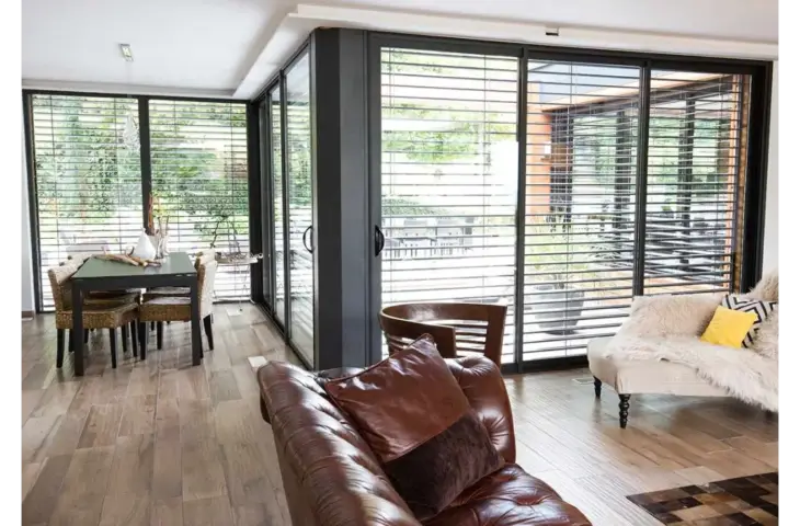 Baie vitrée aluminium avec brise-soleil orientable.